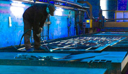 Schneidtische müssen begehbar sein: Werker mit Schneidbrenner auf einem Brennschneidtisch